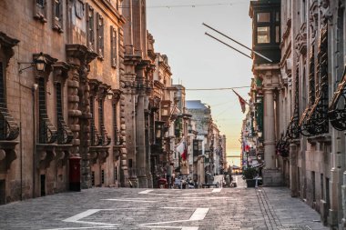 Valletta, Malta şehir manzarası. Valletta 'daki Dar Sokak - Malta' nın başkenti. Geleneksel Malta mimarisi. La Valetta 'nın eski tarihi parçası. Dışarıda insanlar ve dar sokaklar, Malta.