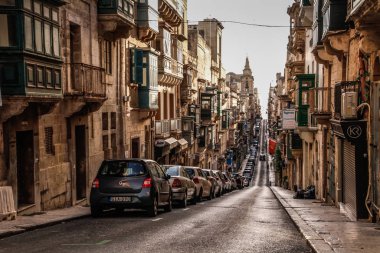 Valletta, Malta şehir manzarası. Valletta 'daki Dar Sokak - Malta' nın başkenti. Geleneksel Malta mimarisi. La Valetta 'nın eski tarihi parçası. Dışarıda insanlar ve dar sokaklar, Malta.
