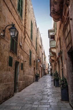Valletta, Malta şehir manzarası. Valletta 'daki Dar Sokak - Malta' nın başkenti. Geleneksel Malta mimarisi. La Valetta 'nın eski tarihi parçası. Dışarıda insanlar ve dar sokaklar, Malta.