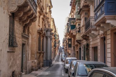 Valletta, Malta şehir manzarası. Valletta 'daki Dar Sokak - Malta' nın başkenti. Geleneksel Malta mimarisi. La Valetta 'nın eski tarihi parçası. Dışarıda insanlar ve dar sokaklar, Malta.