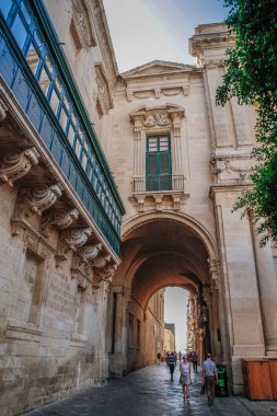 Valletta, Malta şehir manzarası. Valletta 'daki Dar Sokak - Malta' nın başkenti. Geleneksel Malta mimarisi. La Valetta 'nın eski tarihi parçası. Dışarıda insanlar ve dar sokaklar, Malta.
