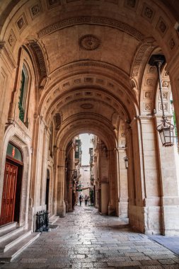 Valletta, Malta şehir manzarası. Valletta 'daki Dar Sokak - Malta' nın başkenti. Geleneksel Malta mimarisi. La Valetta 'nın eski tarihi parçası. Dışarıda insanlar ve dar sokaklar, Malta.