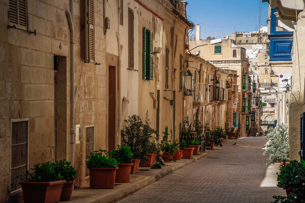 Valletta, Malta cityscape. Narrow street in Valletta - the capital of Malta. Traditional Maltese architecture. Old historical part of La Valetta with people outside and narrow streets, Malta