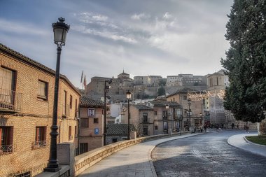 İspanya 'nın tarihi Toledo şehrinin manzarası. Unesco Dünya Mirası Bölgesi. Ortaçağ mimari tarzı olan Alcazar ve Alcantara Köprüsü (Puente de Alcantara) ile aynı caddeye çıktı. Toledo.
