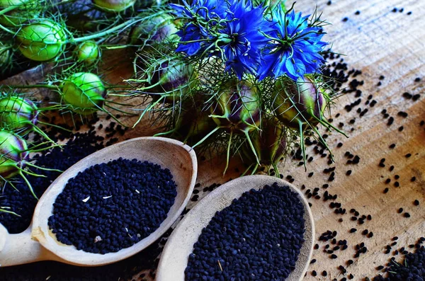 Black cumin (nigella sativa or kalonji) seeds in heart-shaped bowl on wooden background