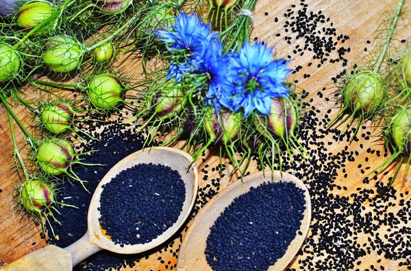 Black cumin (nigella sativa or kalonji) seeds in heart-shaped bowl on wooden background