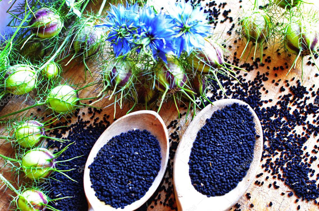 Black cumin (nigella sativa or kalonji) seeds in heart-shaped bowl on wooden background