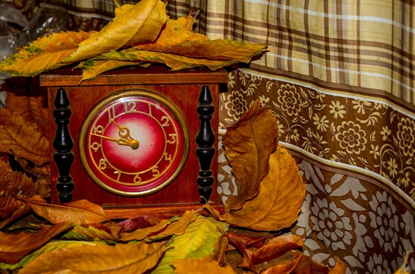 Daylight saving time. Retro styled photo. Vintage black alarm clock on autumn leaves. Time change abstract photo. Daylight saving time (DST)