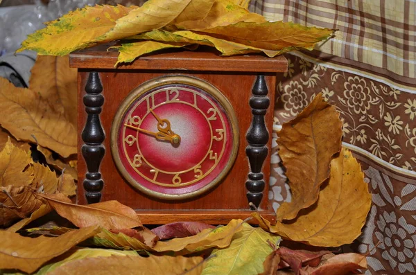 Daylight saving time. Retro styled photo. Vintage black alarm clock on autumn leaves. Time change abstract photo. Daylight saving time (DST)