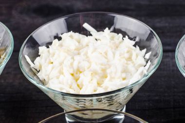 Ahşap bir siyah arka plan üzerine saydam bir derin tabak içinde ezilmiş yumurta haşlanmış tavuk.