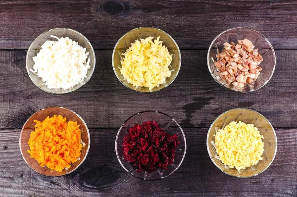 Los ingredientes de la lechuga en los platos separados pequeños. Cebollas ralladas, arenques, zanahorias, remolachas, patatas con salsa blanca y perejil . — Foto de Stock