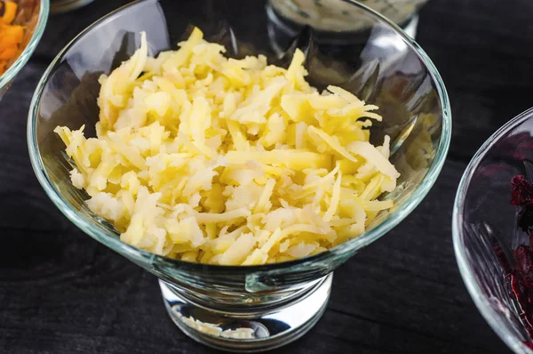 Patatas hervidas trituradas en un plato transparente y profundo sobre un fondo negro de madera . — Foto de Stock