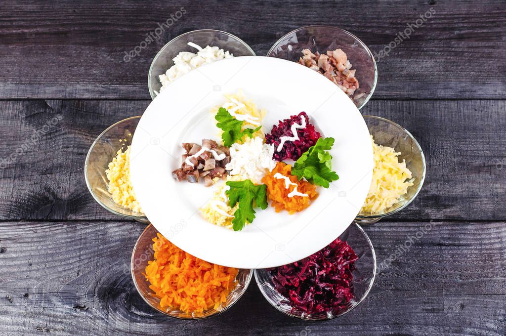 Ingredients of lettuce in separate small plates. Shredded onions, herring, carrots, beets, potatoes with white sauce and parsley.