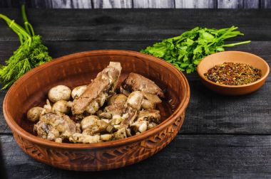 Komposto petrol ve parlak bir tabak, baharat, maydanoz, dereotu soğanlı dana kaburga. siyah ahşap arka plan üzerinde. Fried mantar ve şeffaf levha zeytin.