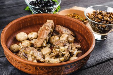 Komposto petrol ve parlak bir tabak, baharat, maydanoz, dereotu soğanlı dana kaburga. siyah ahşap arka plan üzerinde. Fried mantar ve şeffaf levha zeytin.