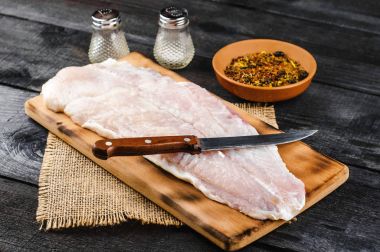 Pangasius fileto baharat ve bıçak siyah ahşap zemin ile ahşap kesme tahtası.