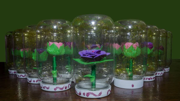 Sentetik el yapımı çiçekler ve bir şişe su ile girmiştir