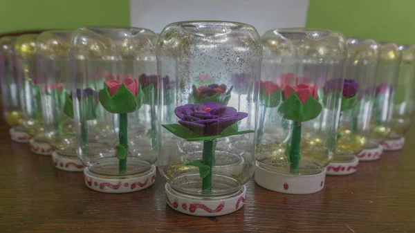 Sentetik el yapımı çiçekler ve bir şişe su ile girmiştir