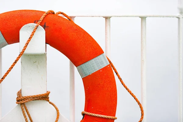 Bouée de sauvetage orange sur mur blanc dans le port — Photo