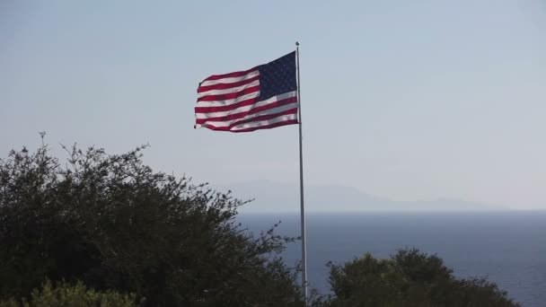 Bandera americana y estadounidense ondeando frente al cielo azul — Vídeo de stock