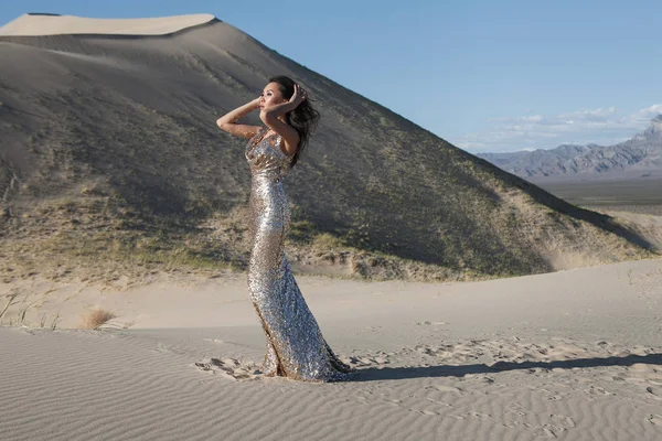 Fashion asian model in a golden shiny dress in a desert