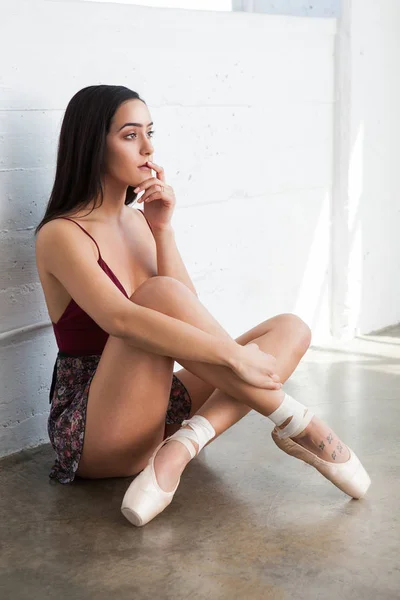 Beautiful dancer woman in pointe shoes is sitting on the floor — Stock Photo, Image