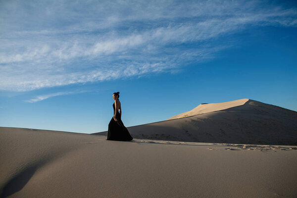 Beautiful asian woman in a long black dress desert landscape