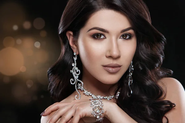 Beautiful woman with luxury jewelry on shiny background