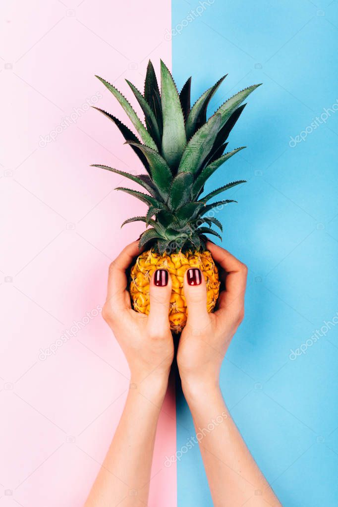 Hands with pineapple on stylish pink