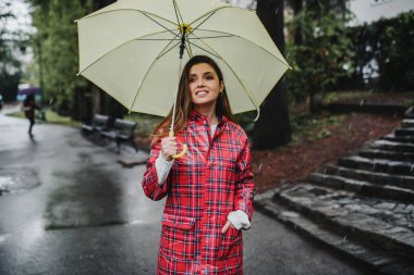 Genç kadın yağmurun altında gülümsüyor ve gülüyor. Doğa ve mutlu hayat kavramı.