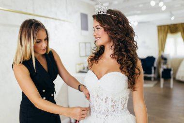 Güzel, genç, esmer kadın gelinliği gelinlik salonunda seçiyor..