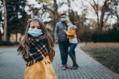 Dışarıda parkta koruyucu maskeli genç bir aile. Hava kirliliği kavramı.