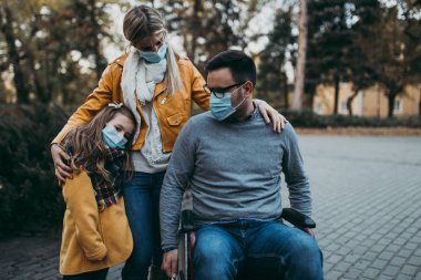 Dışarıda parkta koruyucu maskeli genç bir aile. Hava kirliliği kavramı.