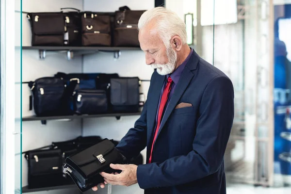 Stylish and modern senior business man choosing and buying clothes and leather goods in expensive store
