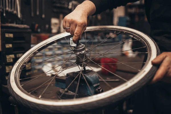 Mechanic repairing a mountain bike in a workshop.