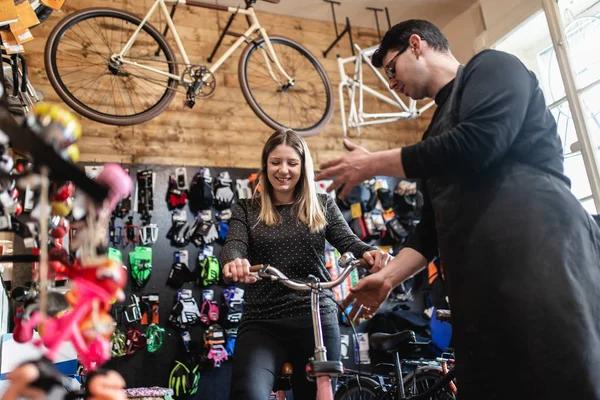 自転車屋で自転車を選ぶ若い女性 — ストック写真
