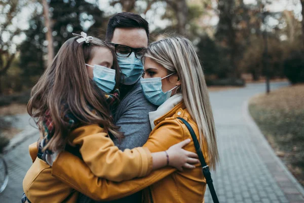 Dışarıda parkta koruyucu maskeli genç bir aile. Hava kirliliği kavramı.