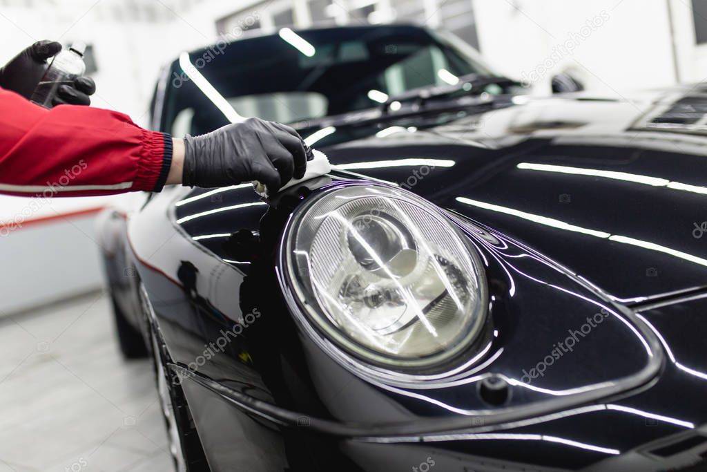 cropped shot of man cleaning car with microfiber cloth, car detailing concept