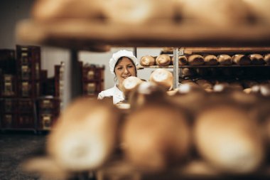 Fırında çalışan ve raflara ekmek koyan genç bir bayan işçi.