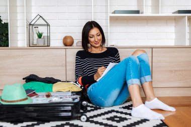 Güzel genç bir kadın eşyalarını büyük bir bavula koyuyor. Seyahat hazırlık konsepti. 