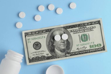 İlaç hapları, yüz dolarlık banknot ve şişe üzerinde mavi arka plan. Kavram iş ve uyuşturucu.