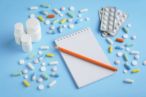 Many different tablets, pills, capsules and notepad with a pencil. Concept self-medication, formula, prescription, choice.