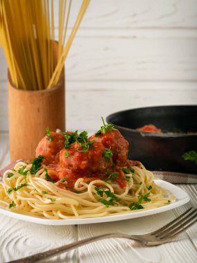 Domates soslu köfteli bir tabak spagetti ve fotokopi alanlı çiğ spagetti.
