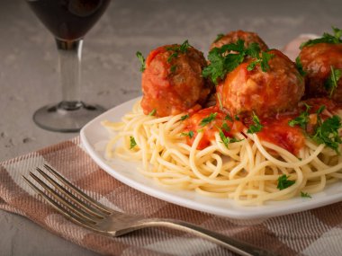 Alçılı arka planda bir bardak şarapla pişirilmiş spagetti ve köfte.