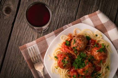 Pişmiş spagetti ve bir bardak şarapla ahşap bir masada köfte.