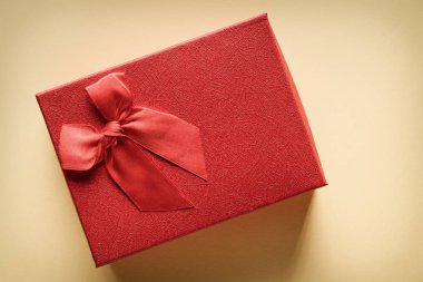 Sarı arka planda kurdelesi olan kırmızı bir hediye kutusunun yakın çekimi: hediye ve romantik ilişki kavramı