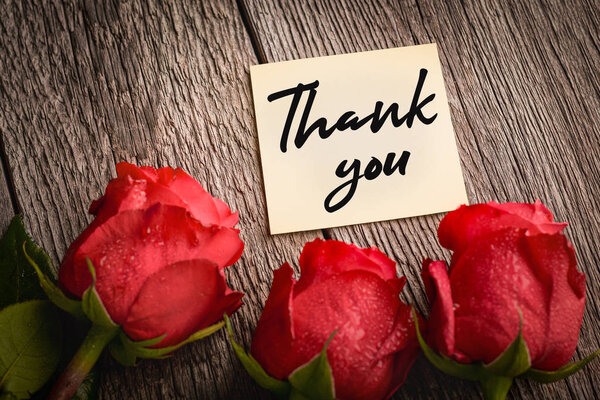 Бумажная записка и красные розовые бутоны на деревянном фоне: концепция будущего
