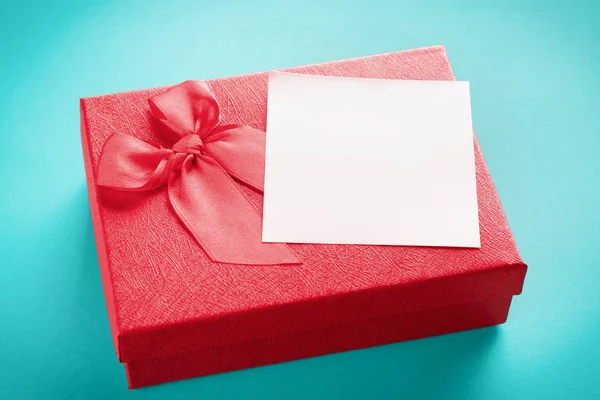 Mavi arkaplandaki kırmızı hediye kutusunu metin için yeri olan boş bir notla kapat — Stok fotoğraf