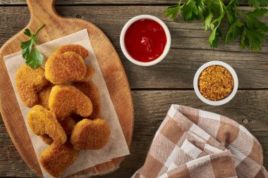 Tahtadaki tavuk külçeleri, domates sosu ve ahşap zemindeki hardal tohumlarının üst görüntüsü.