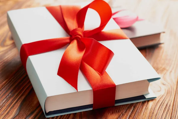 Close-up de um livro amarrado com uma fita com um arco em uma mentira em outro livro: o conceito de um bom livro - um bom presente — Fotografia de Stock
